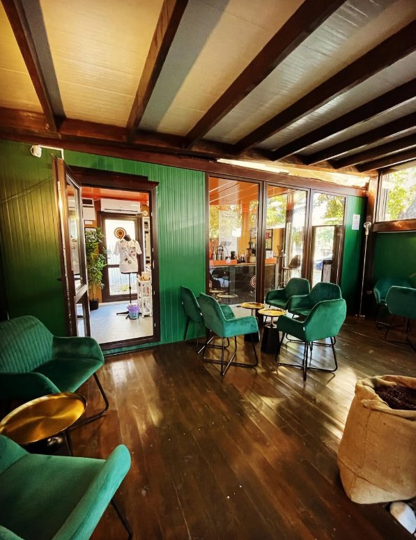 Interiorul Cafenelei 9, cu fotolii din catifea verde, podea de lemn și un sac de cafea proaspăt prăjită